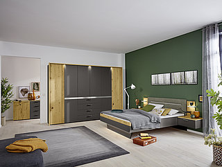 Suggestion 9264: 6-door hinge-door wardrobe, 1. and 6. Door in offset, 4 front drawers, bed unit with upholstered headboard in fabric 8705 (polyester), 2 nightstands with 2 drawers each approx. W 302, H 223, D 60 cm (wardrobe), 180 x 200 cm (bed), approx. W 60, H 48, D 42 cm (nightstand) in matte grey slate lacquer, offset beamed oak