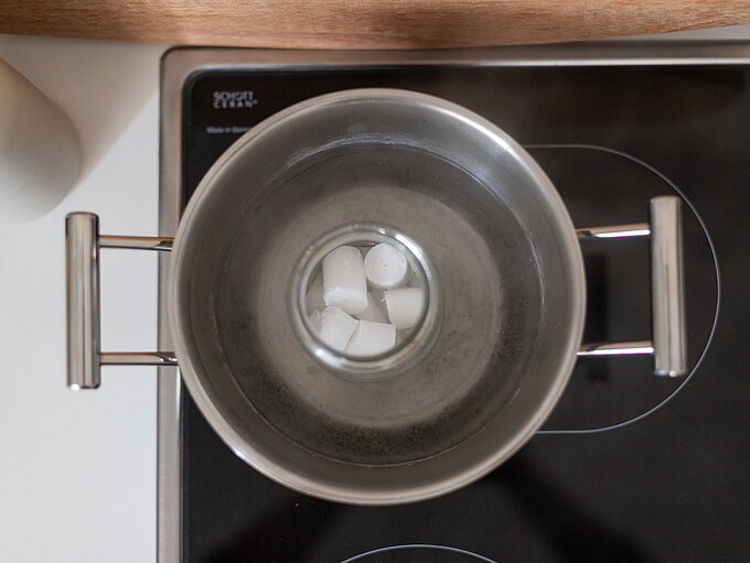 Schritt 2 für ein DIY mit Kerzenresten, Einen Topf mit Wasser zum Kochen bringen und das mit Kerzenresten gefüllte, hitzebeständige Gefäß in das Wasserbad stellen, bis alle Wachsstücke geschmolzen sind.