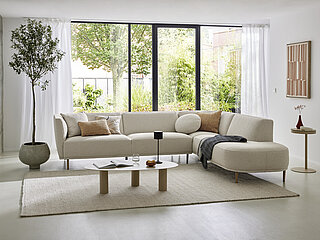 Eckgruppe bestehend aus Anreihsofa 3-sitzig, Armlehne links, Eckottomane, Armlehne rechts, Stoff (PG B, z.B. Partner beige 05), Metallfuß RAL 1019 grey-beige, ca. B 310, H 76, T 210 cm. Zubehör: 2 x Dekokissen ca. 50 x 50, Dekokissen rund, ca. Ø 50, Lendenkissen ca. 50 x 35 cm, Stoff (PG B, z.B. Partner beige 05 oder Discovery cognac 28).