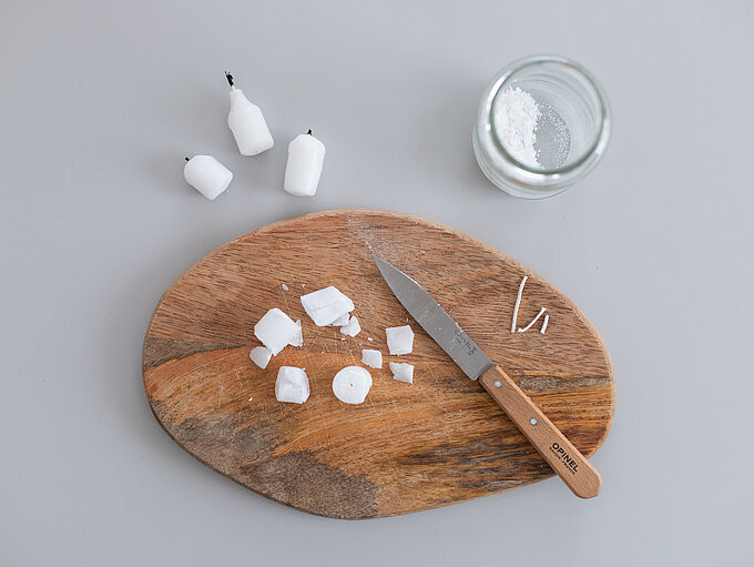 Schritt 1 für ein DIY mit Kerzenresten, Kerzenreste klein schneiden und von Dochtresten befreien. Sollten sich nicht alle lösen lassen, ist das kein Problem. Diese können später aus dem flüssigen Wachs noch vorsichtig entfernt werden. Die Wachsstücke in ein hitzebeständiges Gefäß geben, z.B. ein Glas oder eine Konservendose