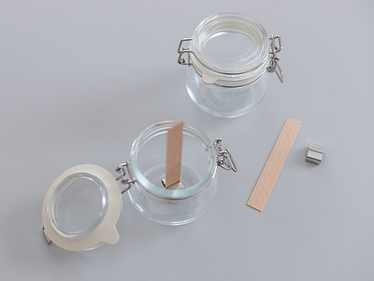 Schritt 4 für ein DIY mit Kerzenresten, Den Holzdocht in die entsprechende Metallvorrichtung stellen und mit einem Wachstropfen am Boden des Glases befestigen.