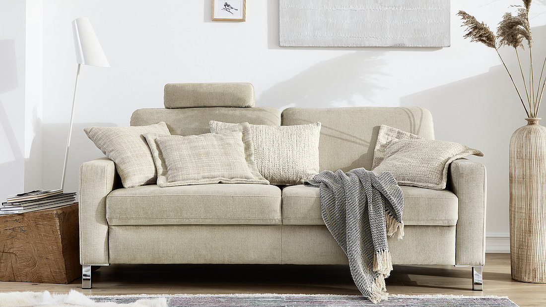 Three-seater sofa (3002) approx. W 190, H 86, SH 47, D 95, SD 58 cm, fabric 10071, light beige (JAB 1), 53% polyester, 40% polyacrylic, 7% viscose, inner spring seating comfort, armrest A, chrome-plated metal feet, headrest (9190) approx. W 50, H 15, T 14 cm, accessories: Oxford cushion (7552) and cushion (9002), fabric 16070, white (JAB 1), Oxford cushion (7550) and cushion (9205), fabric 15070, white (JAB 1)