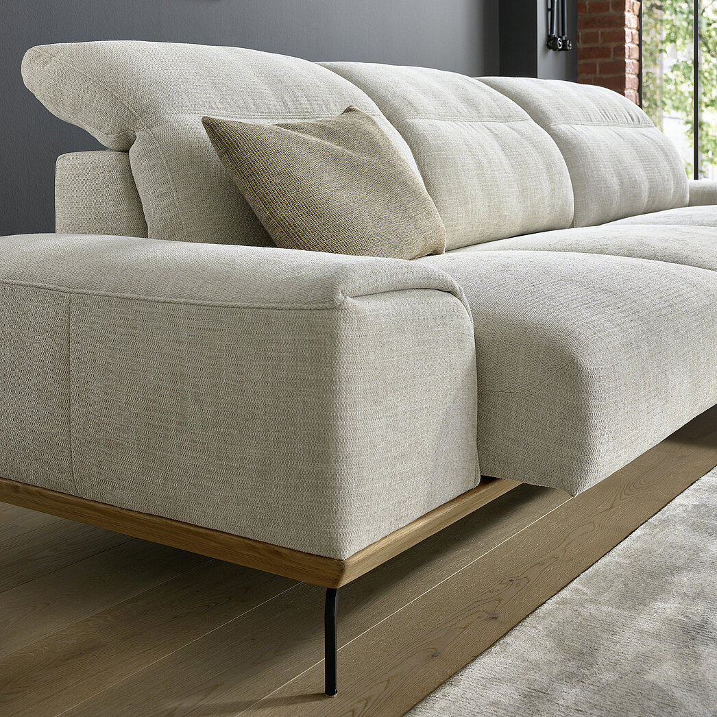 Detail: motorischer Sitzauszug (A02), Kopfstützenverstellung, Stoff S 43/43 creme (SK 20, 100 % Polyester), Sichtholzsockel Eiche (SOE1), Metallfuß (F C3), M99 schwarz